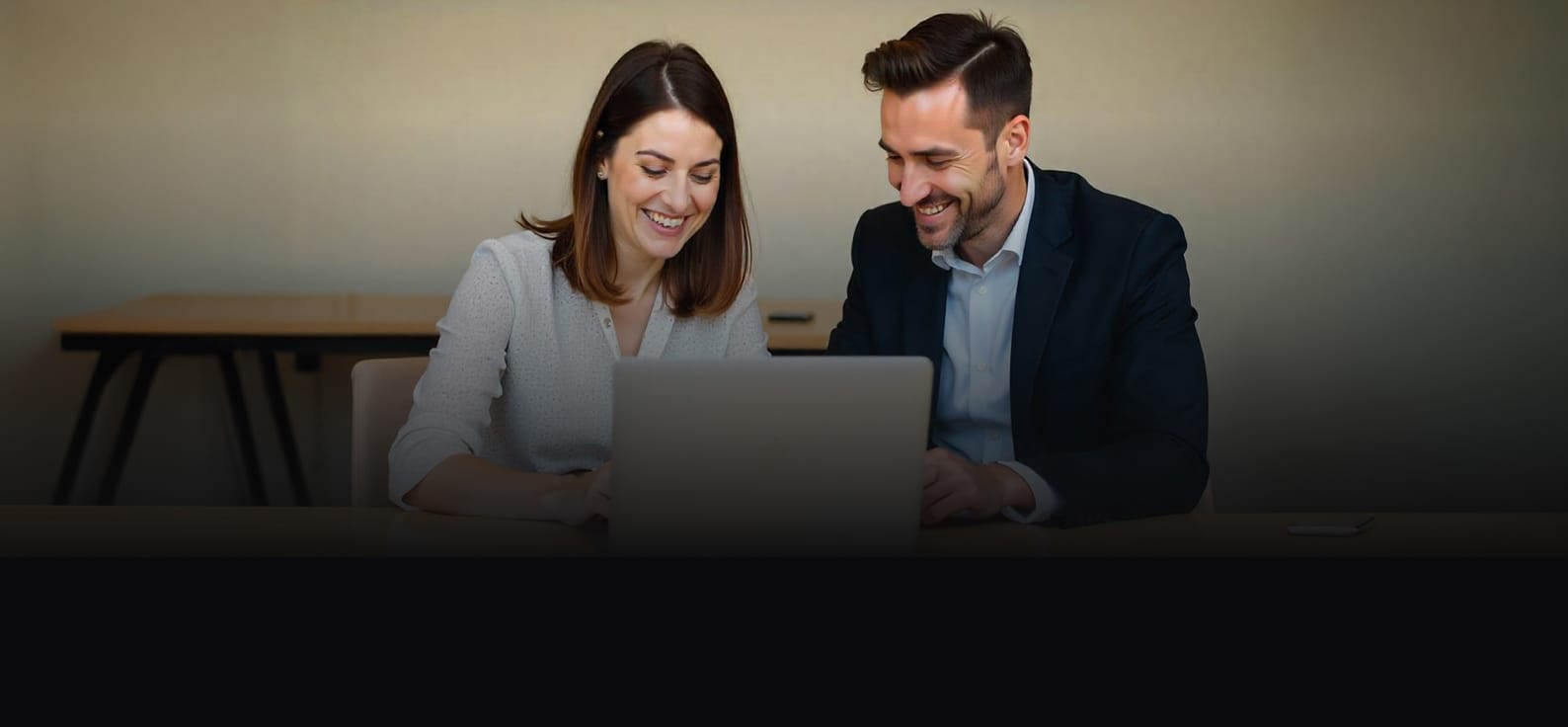 Channel partner and client smiling while collaborating over a laptop.